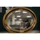 AN OVAL FRAMED MIRROR 85 X 65 CM