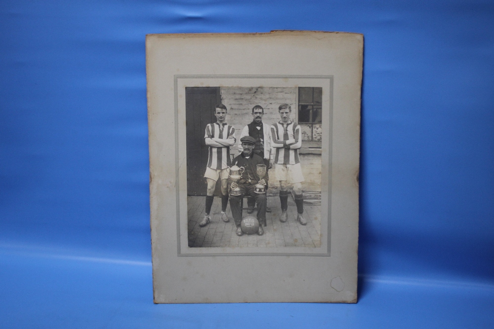 W.U.F.C. 1911-12, a photograph of four men with two trophies and a football, two in sports strip and