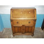 A MID CENTURY OAK WRITING BUREAU WITH LEATHER INLAY ON BUN FEET