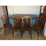 AN ANTIQUE DROP LEAF OAK DINING TABLE AND FOUR WHEEL BACKED CHAIRS