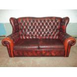 A THREE SEATER VINTAGE OXBLOOD LEATHER WINGED BACK CHESTERFIELD STYLE SOFA