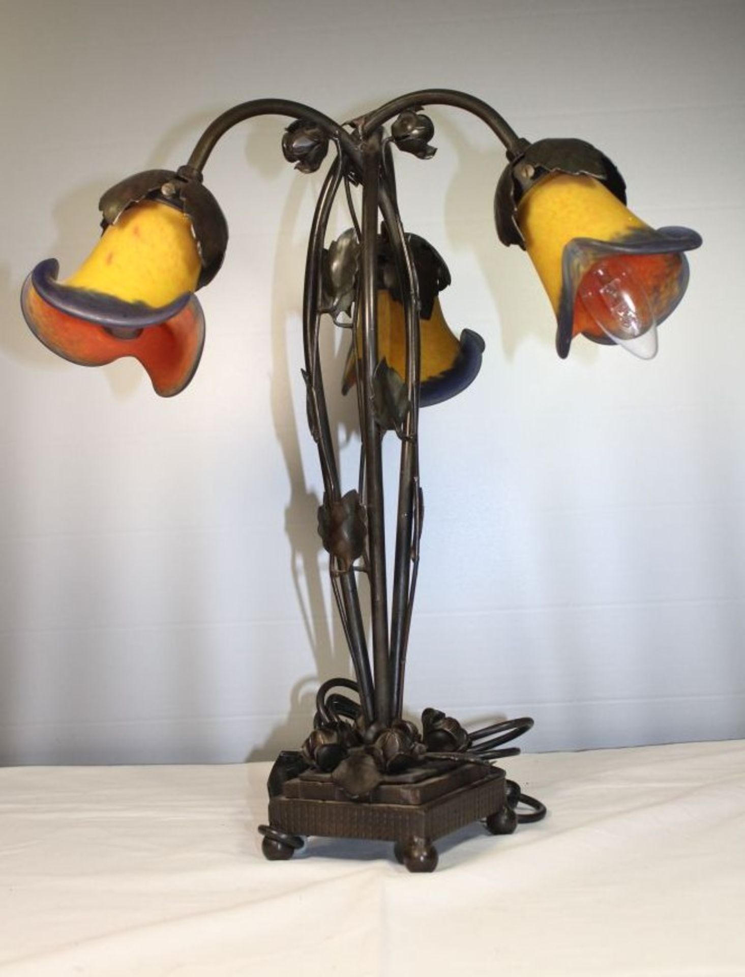 3flammige Tischlampe im Jugendstil, 20. Jhd., Kunstglasschirme, bronzierter Metallstand, H-47cm.