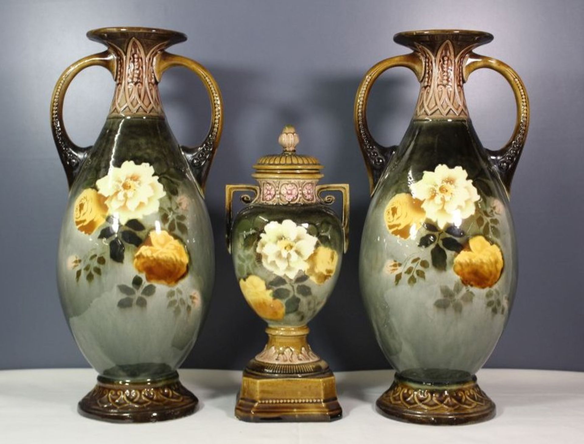 Paar Henkelvasen sowie kleinere Deckelvase, Rosenbemalung in Unterglasur, 1x Vase Stand bestossen,