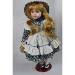 Doll on stand in navy and white pinafore dress