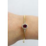 18ct gold hinged bangle set with round cut diamonds and an 8.2 x 6.6mm ruby. Edwardian era - turn of