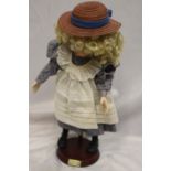 Doll on stand in blue and cream pinafore