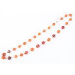 A gilt metal and carnelian necklace formed of rounded beads (and one faceted bead) of vari-