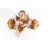 A pair of early 20th century gilt cherub head wall hangings together with a painted model of a