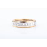 An 18ct white and yellow gold and diamond ring the band channel-set with nine princess-cut