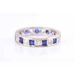 A blue and white stone eternity ring set with cubic zirconias, the engraved white metal mount