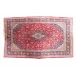 A large 20th century hand woven Persian Kashan carpetwith central medallion on a red ground field