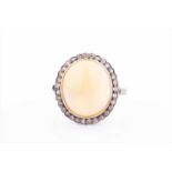 A yellow gold, diamond, and opal cluster ringset with a rounded oval cabochon opal, within a