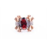 A late Art Deco gold and garnet cocktail ringset with a mixed-cut garnet, the mount with ornate