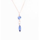 An 18ct rose gold, diamond, and sapphire pendant set with a mixed pear-cut sapphire, a baguette-