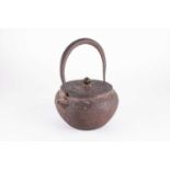 An early Japanese cast iron teapotpossibly 17/18th century, with hoop handle and short spout, the