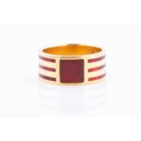 A yellow metal and cornelian signet ring with three champlevé enamel red bands encircling the