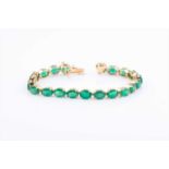 A yellow metal and emerald line braceletset with twenty-one mixed oval-cut emeralds, approximately