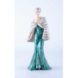 An Art Deco Goldscheider figure of an elegant lady in a green lace flowing dress, her shoulders