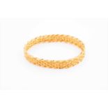 A yellow metal bangle braceletof textured ribbon-twist design, marked 22ct, internal diameter