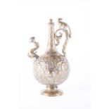 An Indian brass pedestal ewer bearing the embossed face of Shiva, decorated elsewhere with birds and