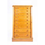 A Victorian light oak Wellington chestcomprising nine graduated drawers with turned wooden