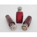 Three Victorian cranberry glass scent bottles, Two double ended with silver plated screw and