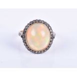 A diamond and opal cluster ring, set with a rounded oval cabochon opal, within a silvered border set
