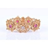A yellow metal floral filigree segment bracelet, each floral design centred with a white or red