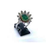 A handmade 18ct white gold, emerald and diamond flower head ring, the central emerald of good colour