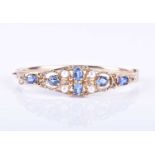 A 9ct yellow gold, sapphire, and pearl hinged bangle, set with six mixed oval-cut sapphires and four