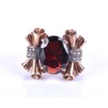 A late Art Deco gold and garnet cocktail ring, set with a mixed-cut garnet, the mount with ornate