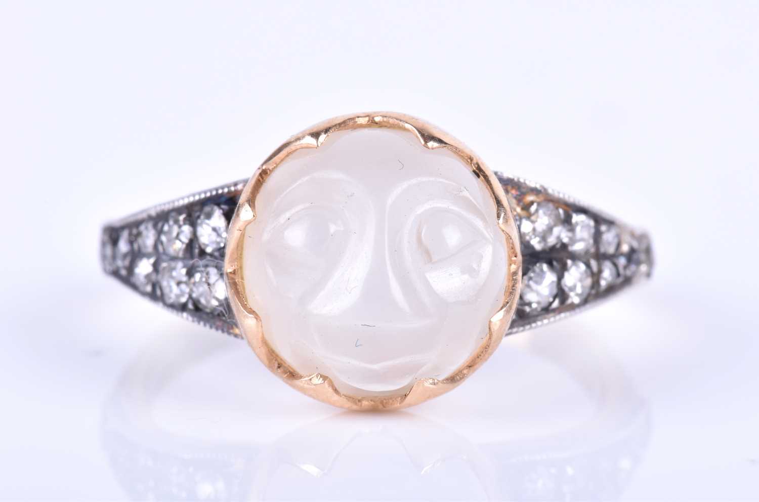 An unusual carved moonstone ring, centred with a moonstone carved in the form of a face, the tapered