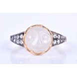 An unusual carved moonstone ring, centred with a moonstone carved in the form of a face, the tapered