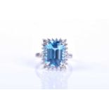 An 18ct white gold, diamond and blue topaz cluster ring, set with a mixed emerald-cut topaz of