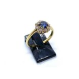 An 18ct yellow gold, sapphire and diamond cluster ring, the central sapphire in a claw setting