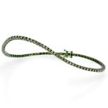 Frost of London. An 18ct white gold and green rhodium plated green diamond tennis bracelet, set with