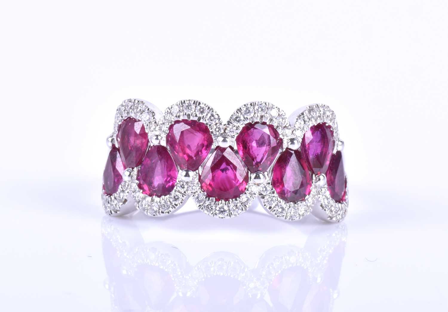 An 18ct white gold, diamond and ruby ring, the rounded mount set with a row of mixed pear-cut rubies