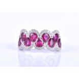 An 18ct white gold, diamond and ruby ring, the rounded mount set with a row of mixed pear-cut rubies