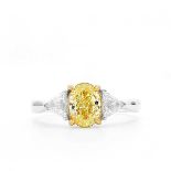 An 18ct white gold and fancy yellow diamond ring, centred with a mixed oval-cut yellow diamond of