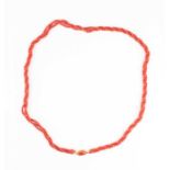 A triple strand coral necklace, comprised of rounded beads, with oval-shaped yellow metal and