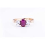 A 9 carat gold ruby and diamond ring, centred mixed oval-cut ruby, flanked with two round