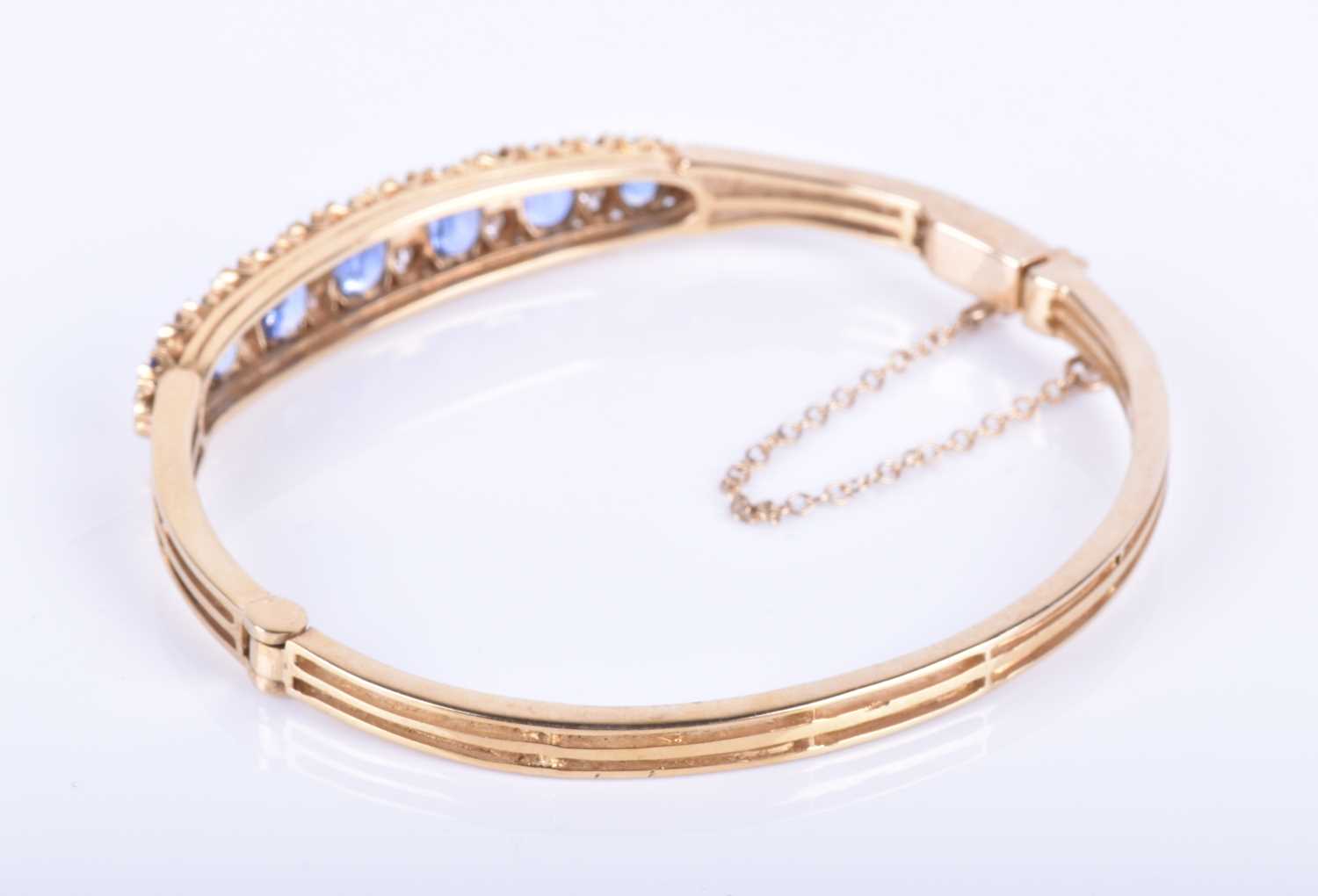 A 9ct yellow gold, diamond and sapphire bangle, set with seven graduated mixed oval cut blue - Image 5 of 6