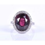 A rubellite tourmaline and diamond cluster ring, set with a mixed oval-cut dark pink tourmaline of