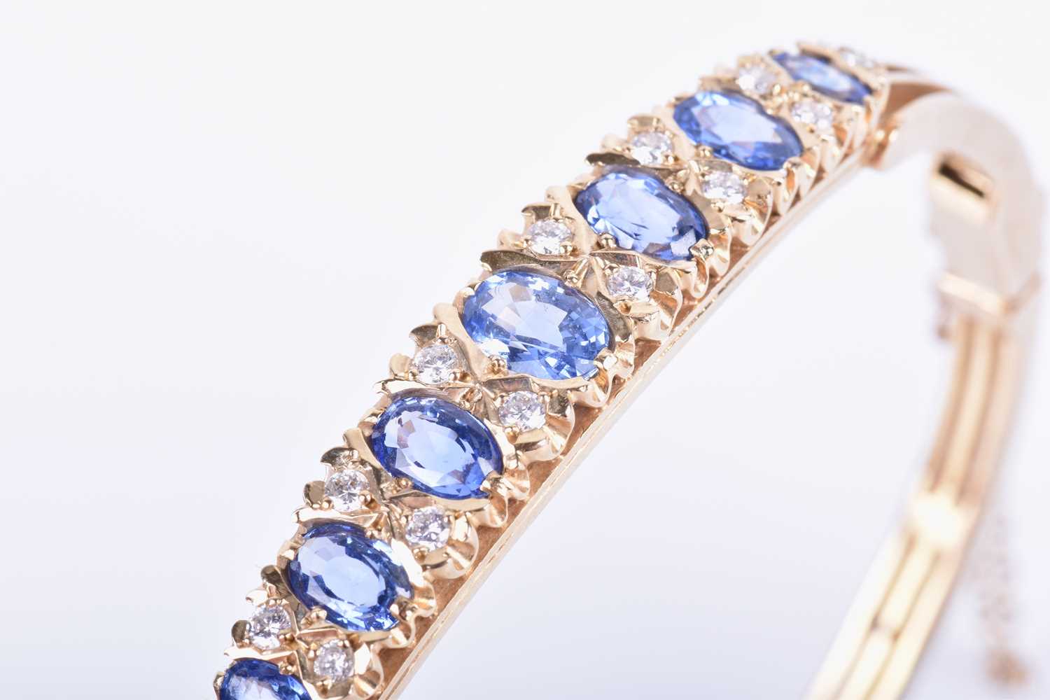 A 9ct yellow gold, diamond and sapphire bangle, set with seven graduated mixed oval cut blue - Image 2 of 6