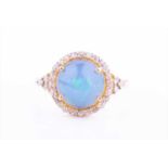 A silver gilt, diamond and opal cocktail ring, set with a round cabochon opal, within a border of