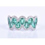 An 18ct white gold, diamond and emerald ring, the rounded mount set with a row of mixed pear-cut