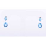 A pair of 14ct white gold and blue topaz drop earrings, each set with two mixed oval-cut topaz,