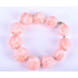 A Chinese carved coral bracelet, the rounded pale pink beads engraved and carved with Chinese