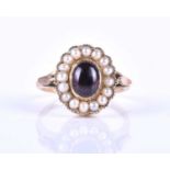 A yellow metal, garnet and pearl ring, set with an oval cabochon garnet, backed setting, within a