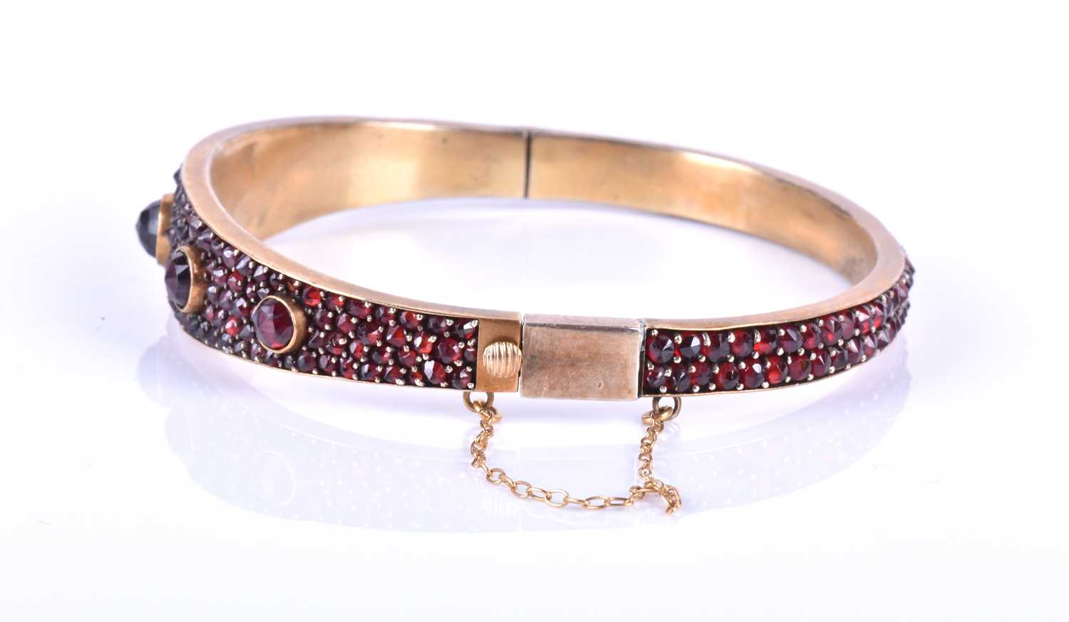 A late Victorian garnet bracelet, the gilt metal hinged bangle set with five collet-set rose-cut - Image 7 of 8